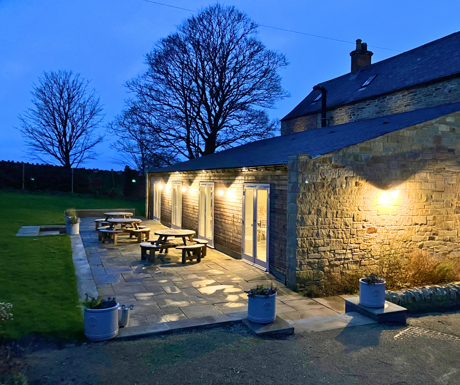 Picnic benches in the private gardens outside Sheffield party venue Manor Oaks House at night.